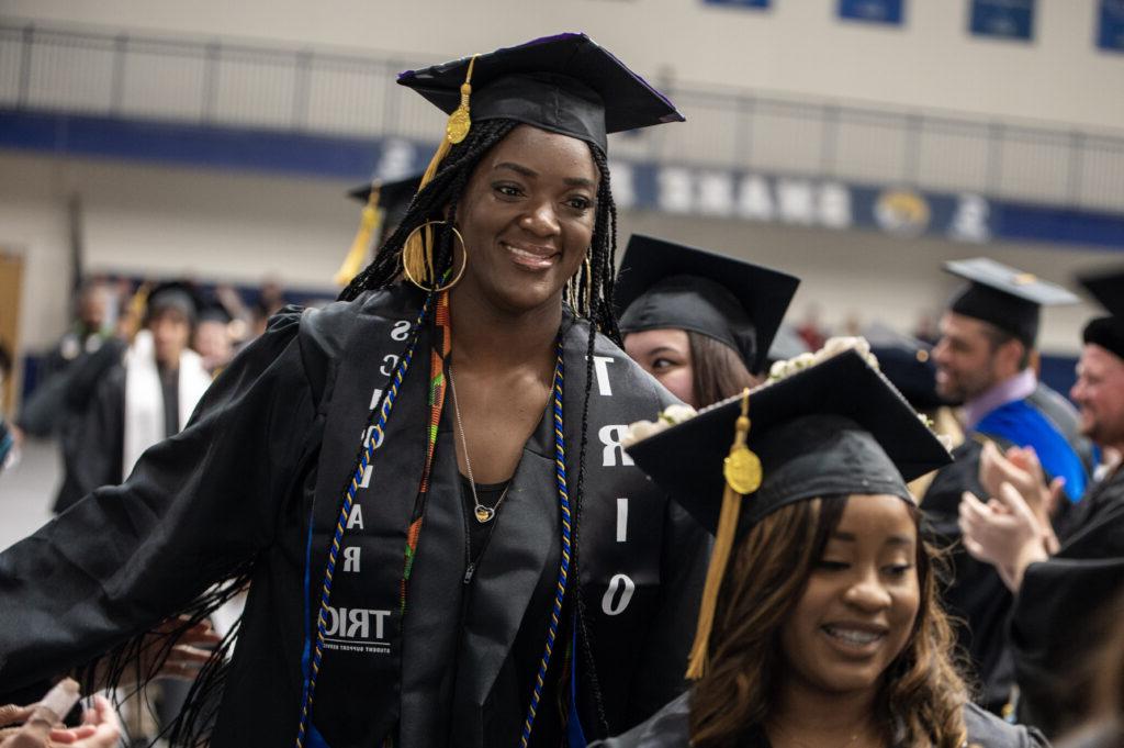 A graduate student stands up to receive her diploma. 